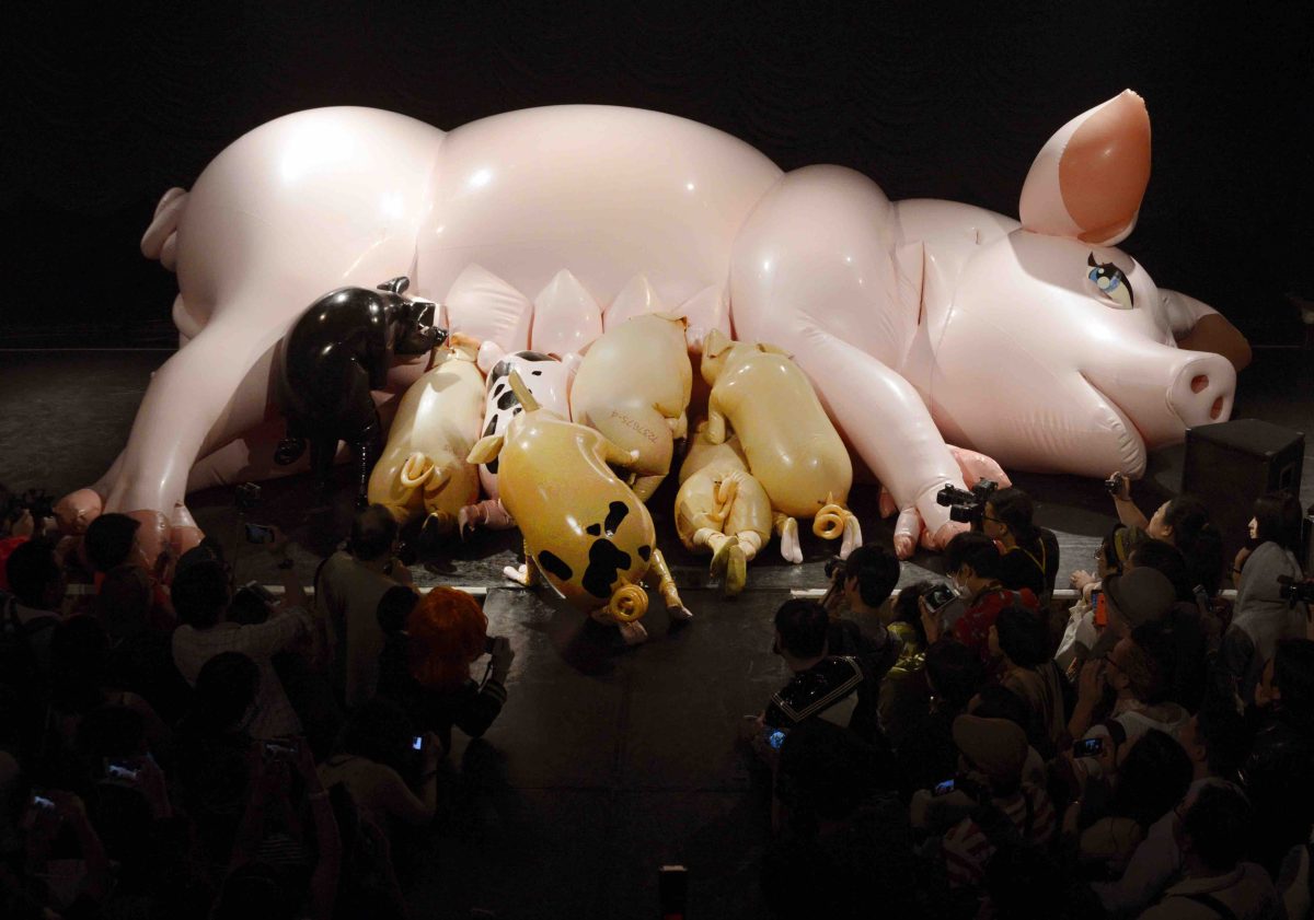 A giant latex pig lies on its side being suckled by smaller latex piggies.