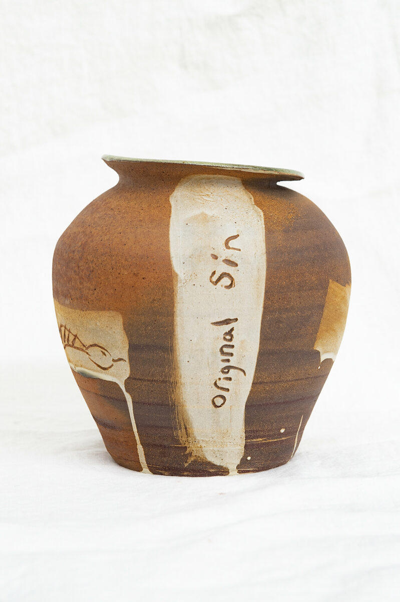 A ceramic pot with the words 'original sin' written into the design.