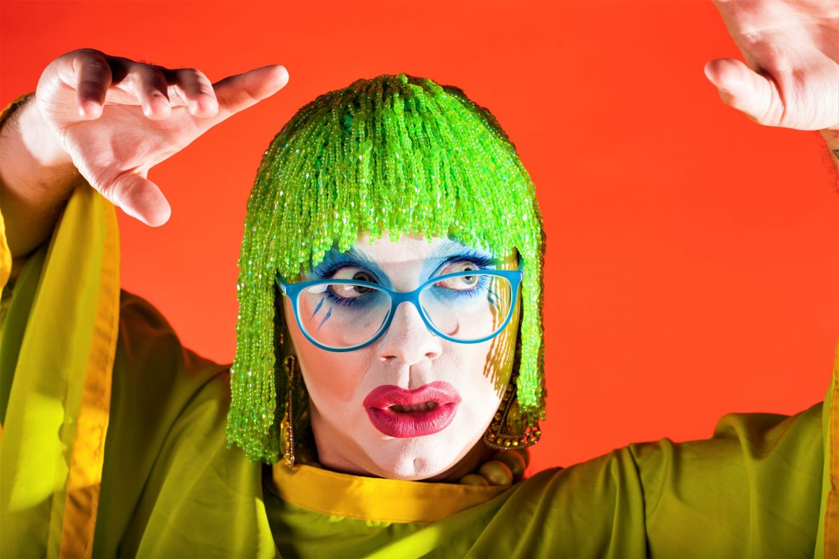 Former FWD artist Ginny Lemon in a green wig against an orange background
