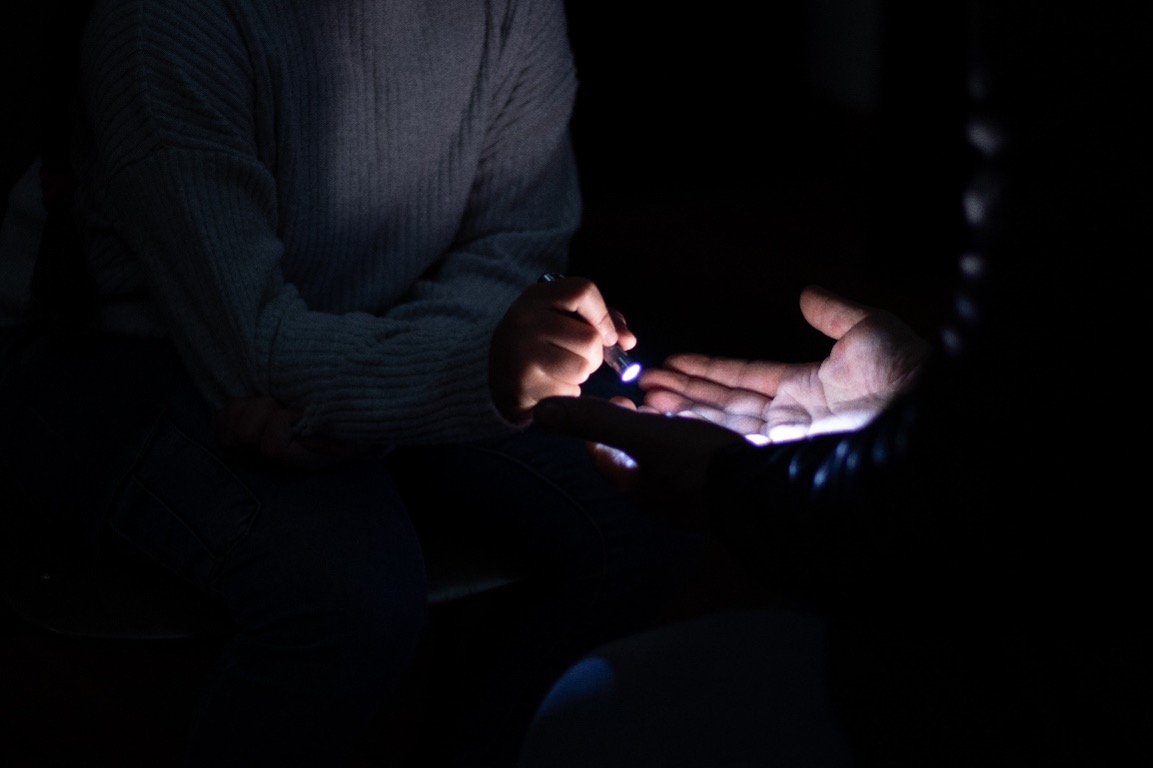 Photo of an open palm illuminated by a torch which is held by a child 